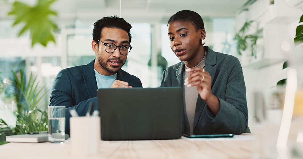 Two colleagues reviewing something together on a laptop