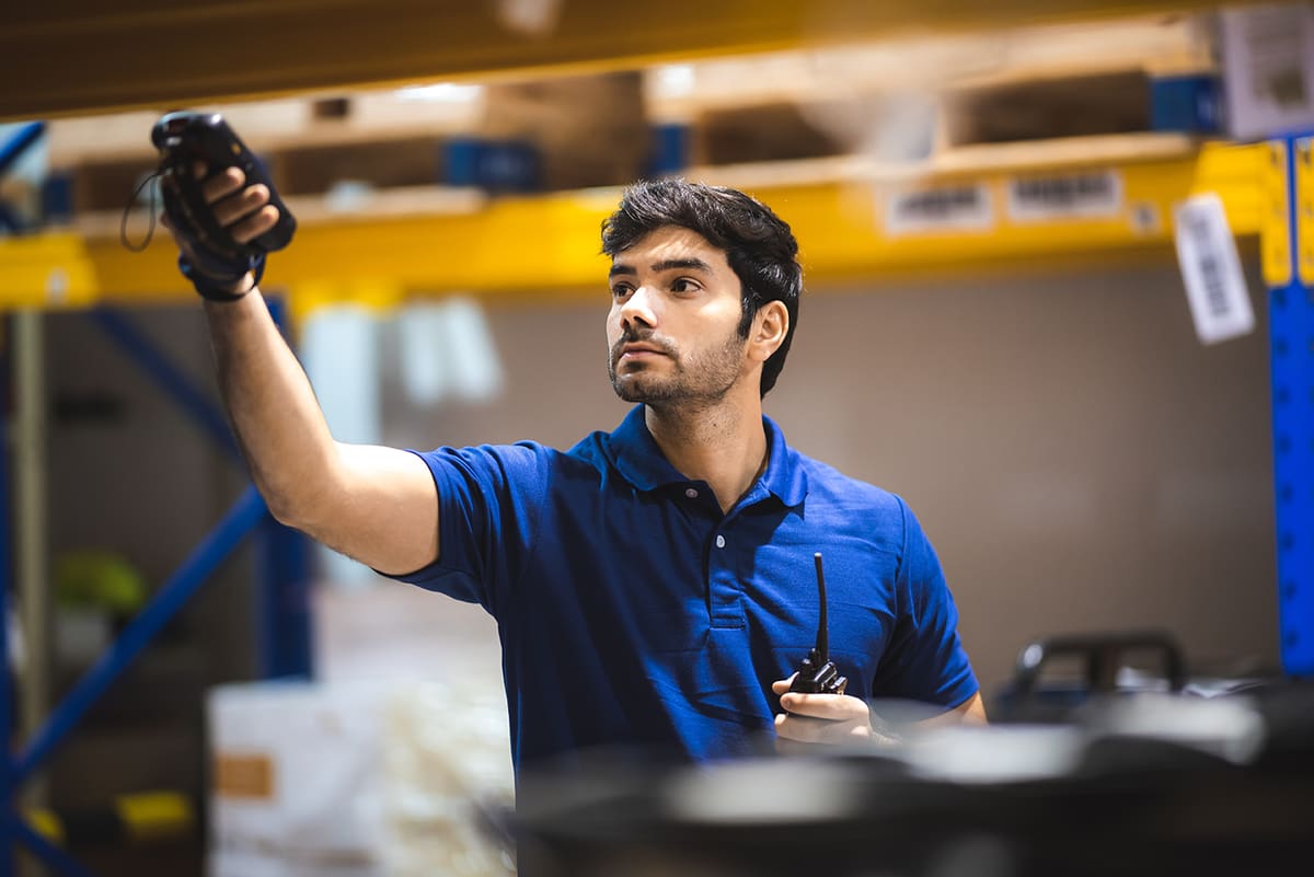 A warehouse apprentice holding a barcode scanner up to a stock shelf
